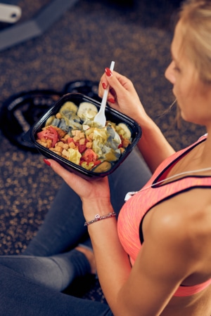 Top view of woman eating healthy food while sitting in a gym. Healthy lifestyle concept