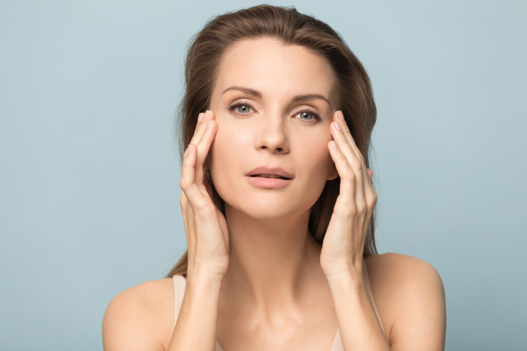 Skinwave facial treatment portrait of young woman with perfect skin touching her face, showcasing natural beauty and healthy skincare results